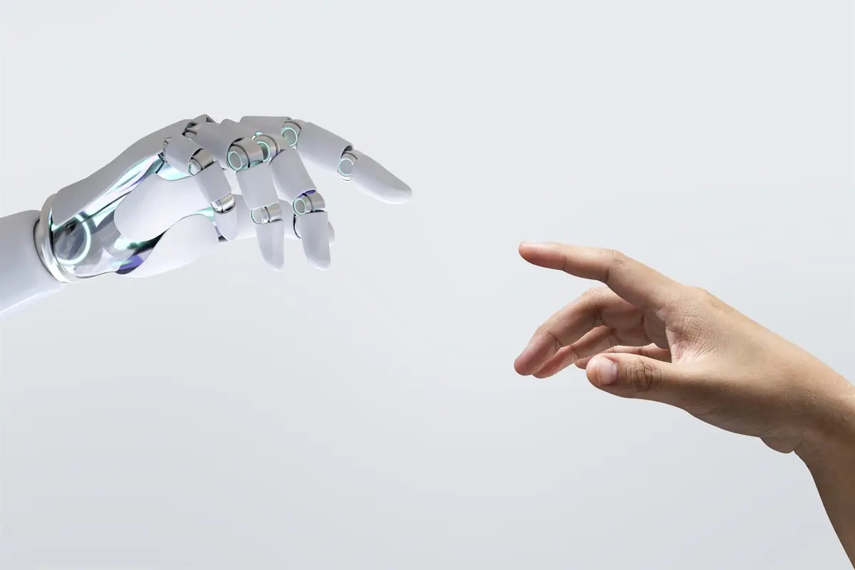 A robotic hand and a human hand reaching towards each other, fingertips almost touching